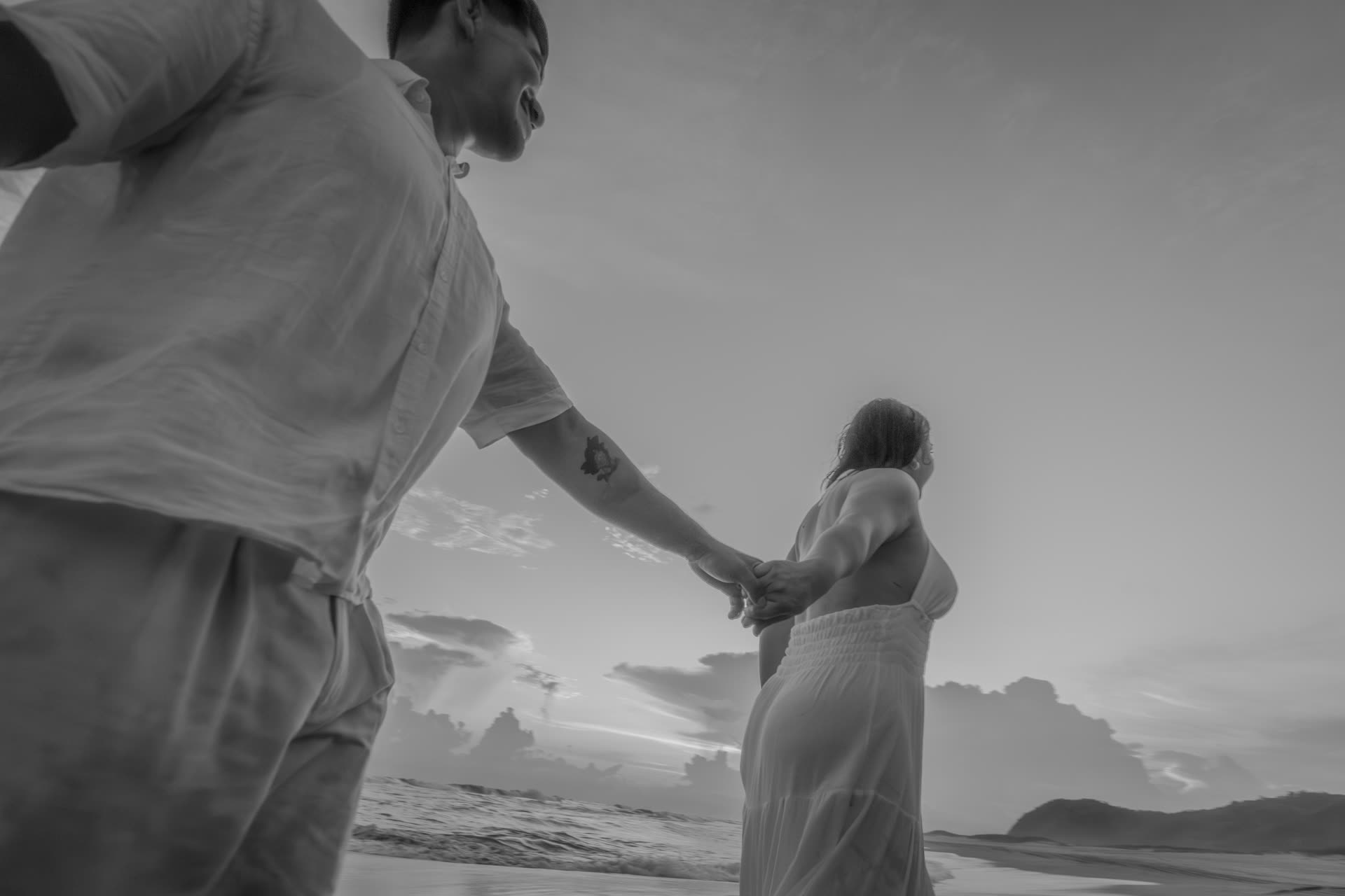 La pareja tomada de la mano junto al mar